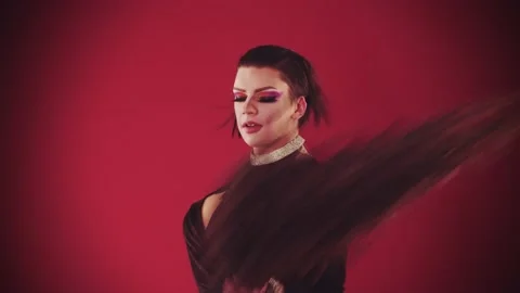 A young man drag artist in extravagant dress on the red background - takes off Stock Footage 149044553