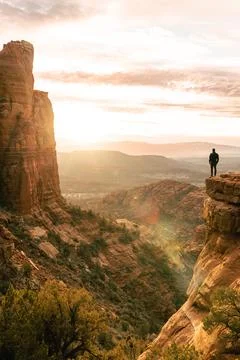 Young man at dramatic cliff at sunset at Cathedral Rock Sedona Stock Photos