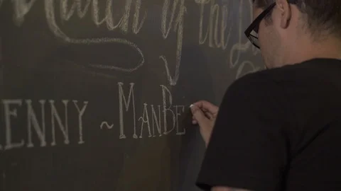 Young man drawing chalk on black board in bar pub. Waiter writing menu on chalk Stock Footage 104530748