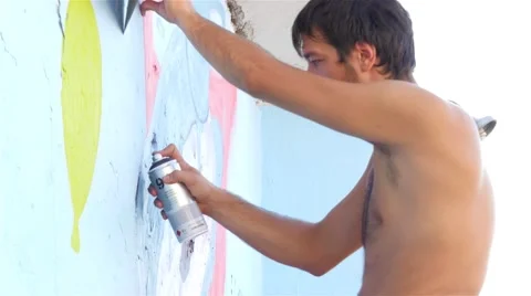 Young man drawing graffiti on wall, tilt down, street artists painting, 4k. Stock Footage 54757435