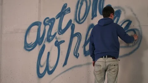 Young man drawing graffiti on a wall with a spray can Видео 74391006