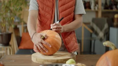 A young man is drawing a pattern on a pumpkin Stock Photos