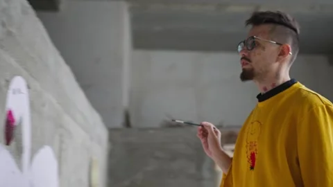 Young man draws graffiti or murals on a concrete wall Stock Footage 270364645