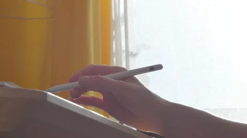 A young man draws with a pen on a tablet pc Stock Footage 220337334
