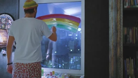A young man draws a rainbow on the window Stock Footage 143925535