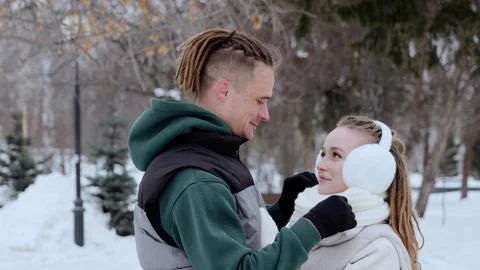 Young man with dreadlocks adjusting the white scarf of his smiling girlfriend Stock Photos