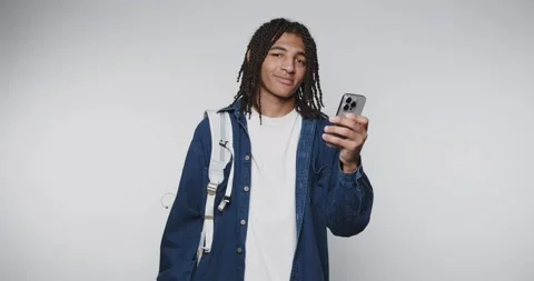 Young man with dreadlocks holding a smartphone, wearing casual clothes. Stock Footage 315161194