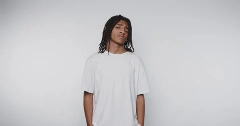 Young man with dreadlocks poses in a minimalistic studio against a plain ba.. Stock Footage 313951139