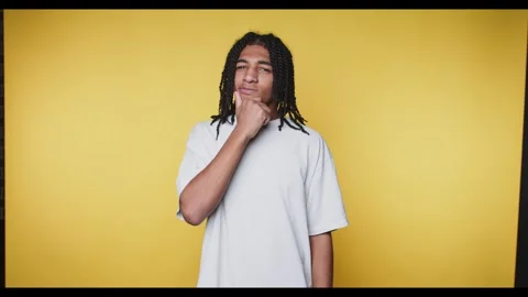 Young man with dreadlocks in a thoughtful pose against a yellow background. Stock Footage 315162887