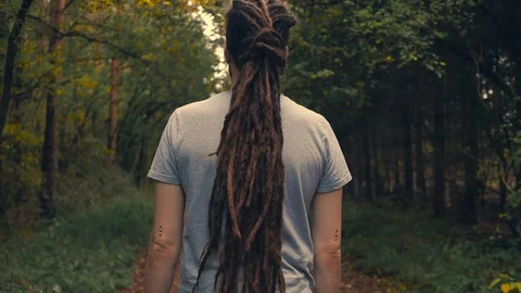 Young man with dreadlocks walking through woodlands. Stock Footage