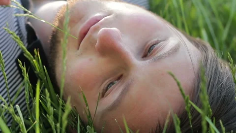 A young man dreamer lying on the grass and thinking about something pleasant 库存影片 90311045