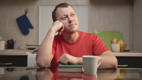 Young man dreams sitting at the kitchen table at home Stock Footage 130656820