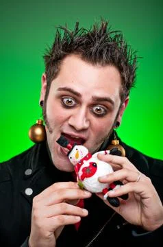 Young man dressed as an emo goth eating a christmas ornament Stock Photos