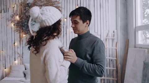 Young man dressed in a gray sweater, gives his girlfriend a Christmas present. Stock Footage 142940095