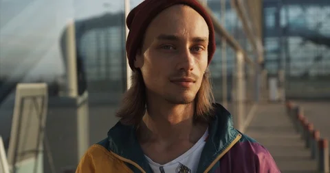 Young man dressed like a hipster smiles straight to the camera standing in the Stock Footage 95276653