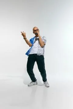 Young man dressed in split-patterned blue and white shirt with glasses, sings Foto stock
