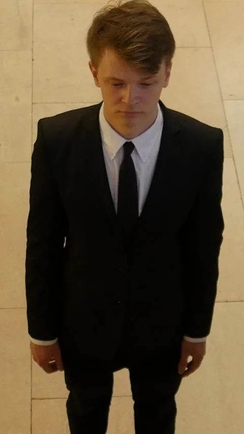 A Young Man Dressed in a Suit with a Pensive and Thoughtful Expression on Vidéo 287846625