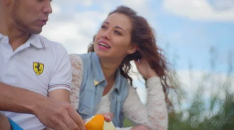 Young man dressed for summer strips off the skin of an orange Stock Footage 60843809