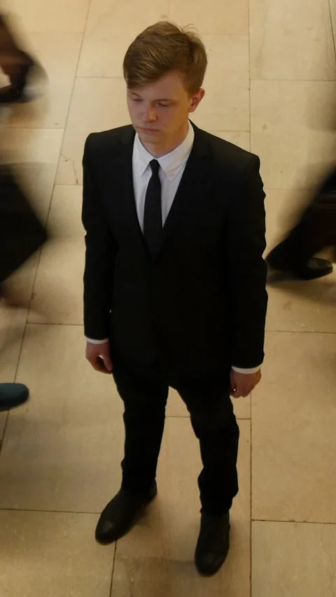 A young man dressed in a tailored suit stands out amidst a bustling and Vidéo 288258251