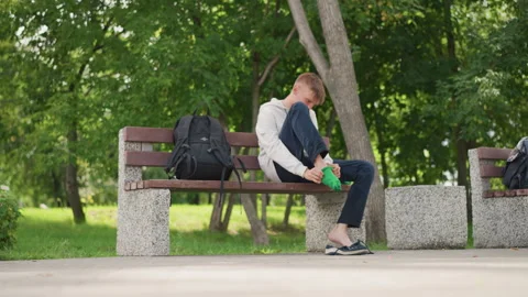 Young man dressing, Individual tending to foot in peaceful surroundings, Young Stock Footage 330965731