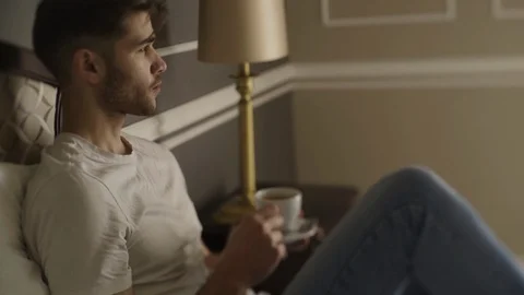 Young man drink coffee sitting on the bed Stock Footage 87146897