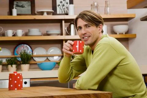 Young man with drink at kitchen table, portrait Stock Photos