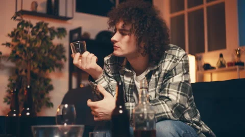 Young man drinking alcohol and kissing a glass, unhealthy lifestyle, hungover Stock Footage 248754928