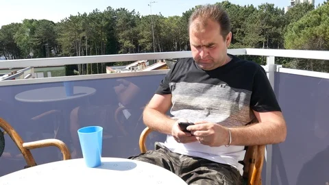 Young man drinking and talking on cellphone on beautiful terrace Stock Footage 90343640