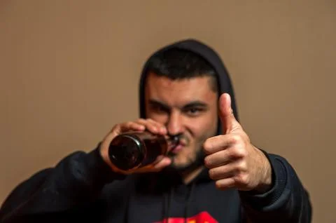 Young man drinking beer and showing thumbs up Stock Photos