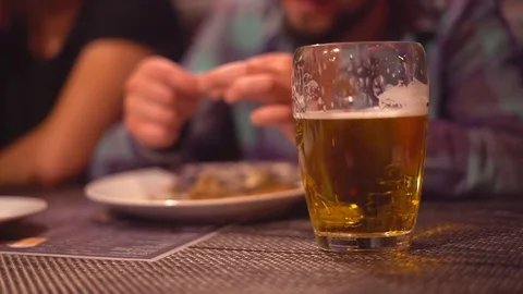 A young man is drinking beer in a bar with dluzyami. Close-up of light beer with Stock Footage 77889775