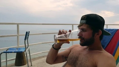 Young man drinking beer at beach 2 Stock Footage 85027160