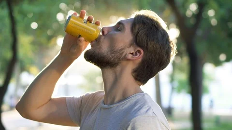 Young man drinking beer from can in park Stock Footage 111778033