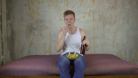 Young man drinking beer at home couch and watching television Stock Footage 82987433