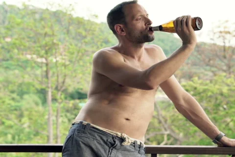 Young man drinking beer standing on the terrace with beautiful, nature view NTSC Stock Footage 51667647
