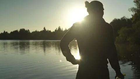 A young man drinking from a bottle by a lake Stock Footage 76223480