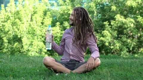 Young man drinking bottle of water with dreadlocks Vídeo Stock 64861868