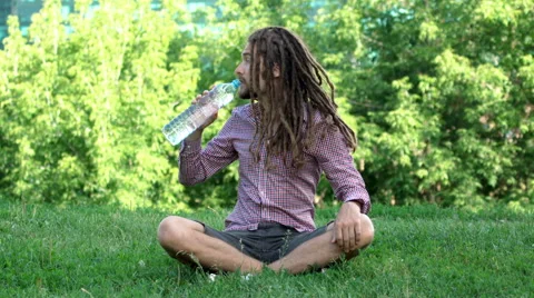 Young man drinking bottle of water with dreadlocks Stock Footage 64862014