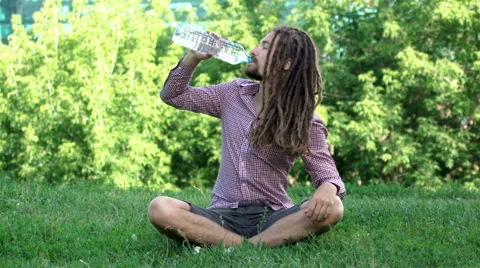 Young man drinking bottle of water with dreadlocks Vídeos de archivo 64862105