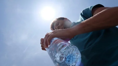 Young man drinking bottle of water standing outdoor in hot summer Stock Footage 92907209