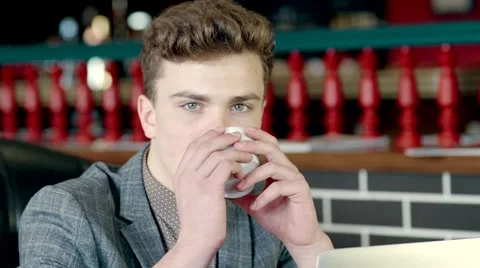 Young man drinking coffee and looking out the window Stock Footage 61388328