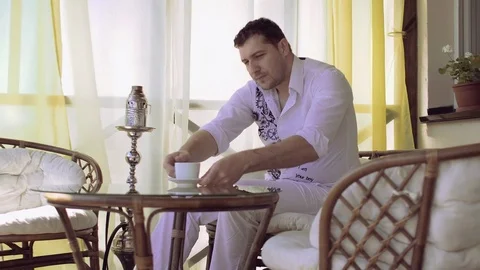 Young man drinking coffee and using smartphone on terrace Stock Footage 81402165