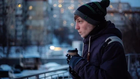 Young man drinking coffee and having cold while waiting someone outside on Stock Footage 86333409
