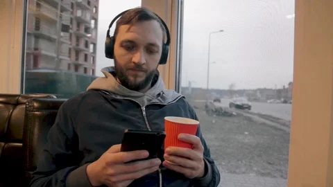 Young man drinking coffee and listening music indoor. Male enjoying music Stock Footage 104732083
