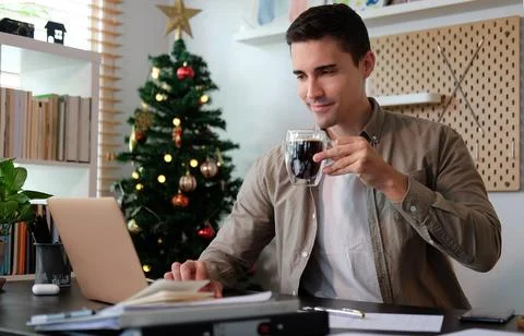 Young man drinking coffee and working on laptop computer.. Stock Photos