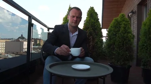 Young man drinking coffee on the balcony. Slow motion Stock Footage 164108604