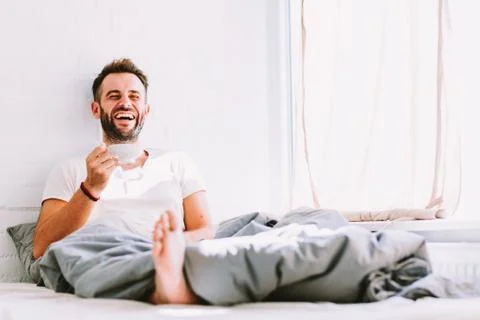 Young man drinking coffee in bed Stock Photos