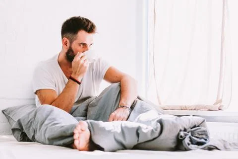 Young man drinking coffee in bed Stock Photos