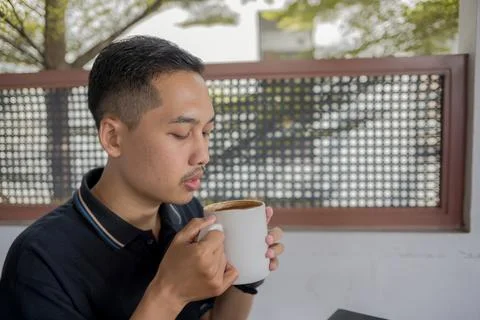 Young Man Drinking Coffee With Both Hands, Enjoying A Moment Of Relaxation .. Stock Photos