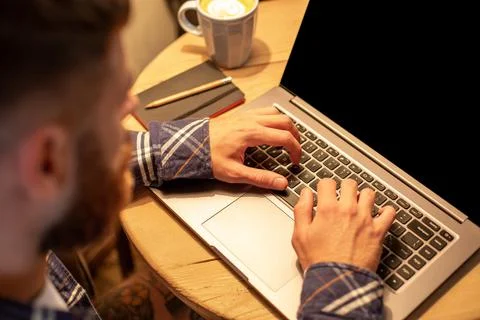 Young man drinking coffee in cafe and using laptop. Man's hands using laptop Stock Photos