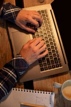 Young man drinking coffee in cafe and using laptop. Man's hands using laptop Stock Photos